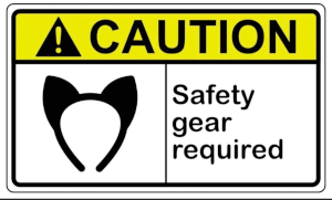 A sign that reads 'caution safety gear required' in clear, uppercase text. A silhouette of a headband with cat ears on it is also seen on the sign